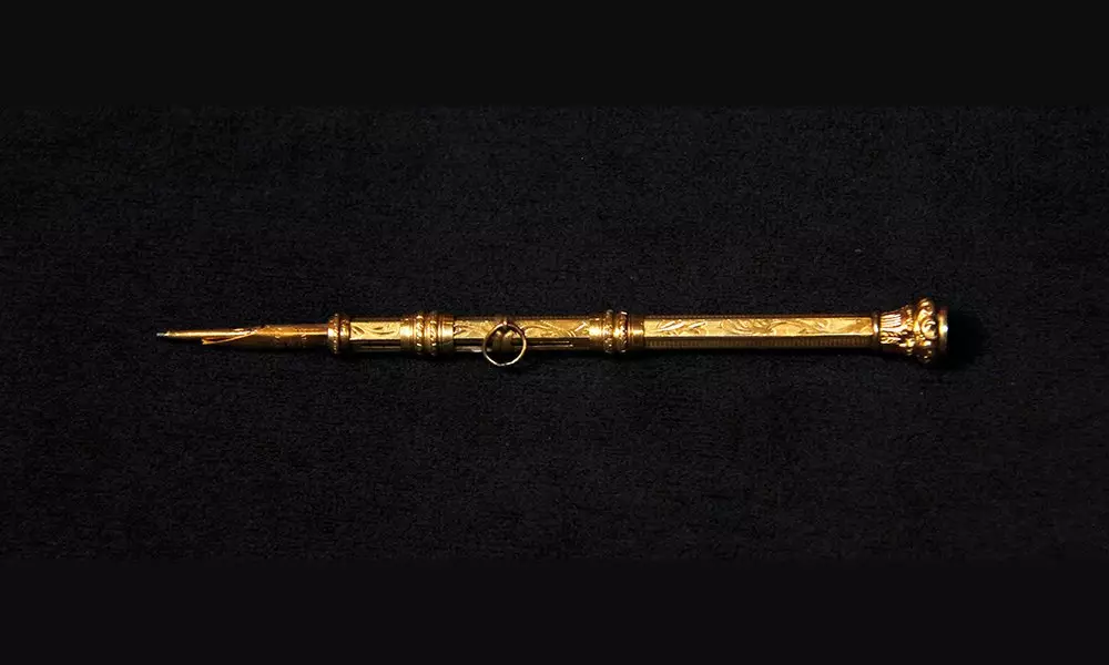 Golden ornate pen/pencil photographed on a dark background