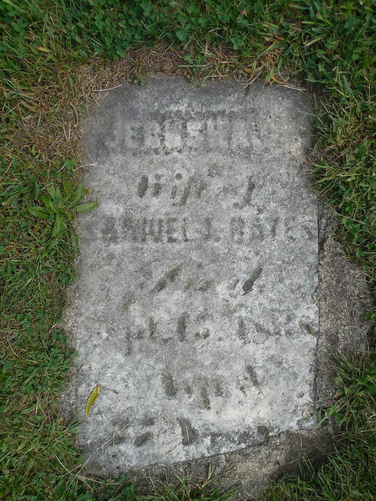 Flat gravestone surrounded by mowed grass.