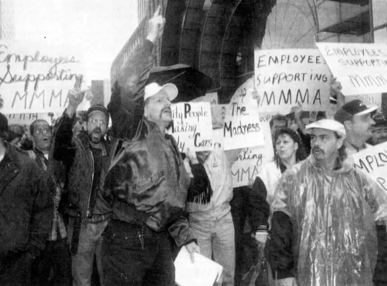 Men and women standing in the raining holding posters that say Employees supporting MMMA