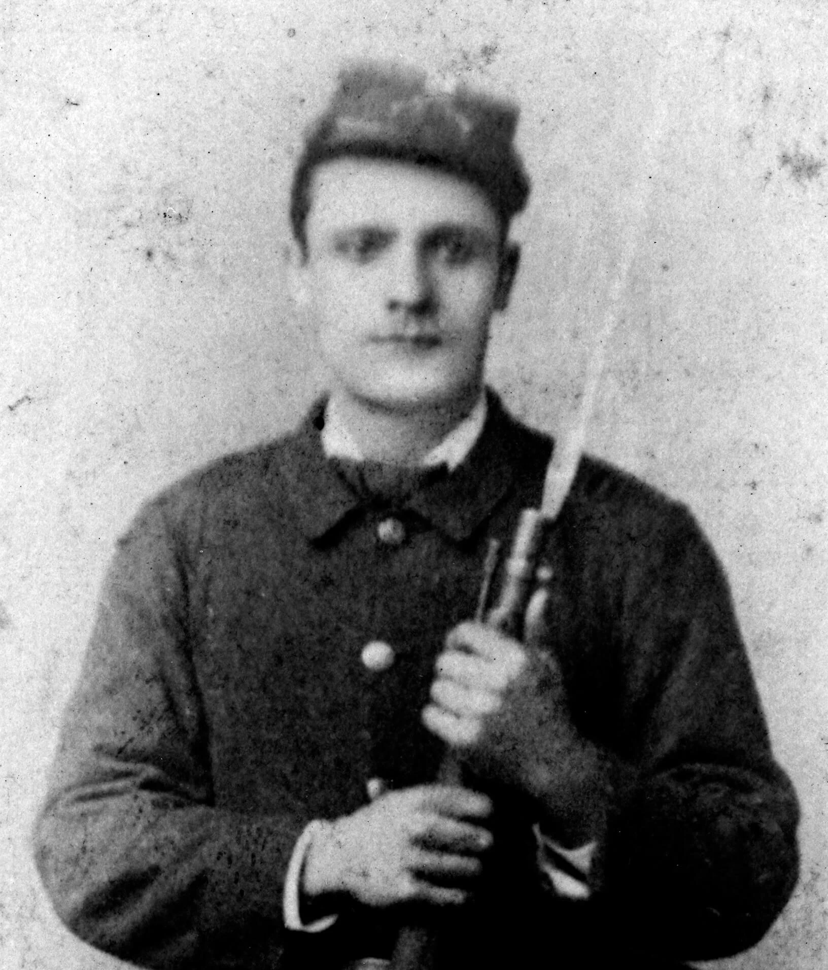 Portrait of Phillip O'Neil, dressed in a military uniform and holding a rifle.