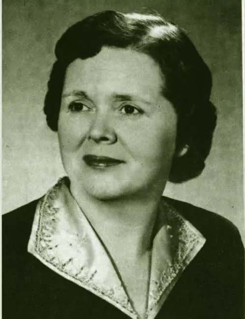 portrait of a light-skinned woman with short wavy hair. Her collar has some embroidered beads on it.