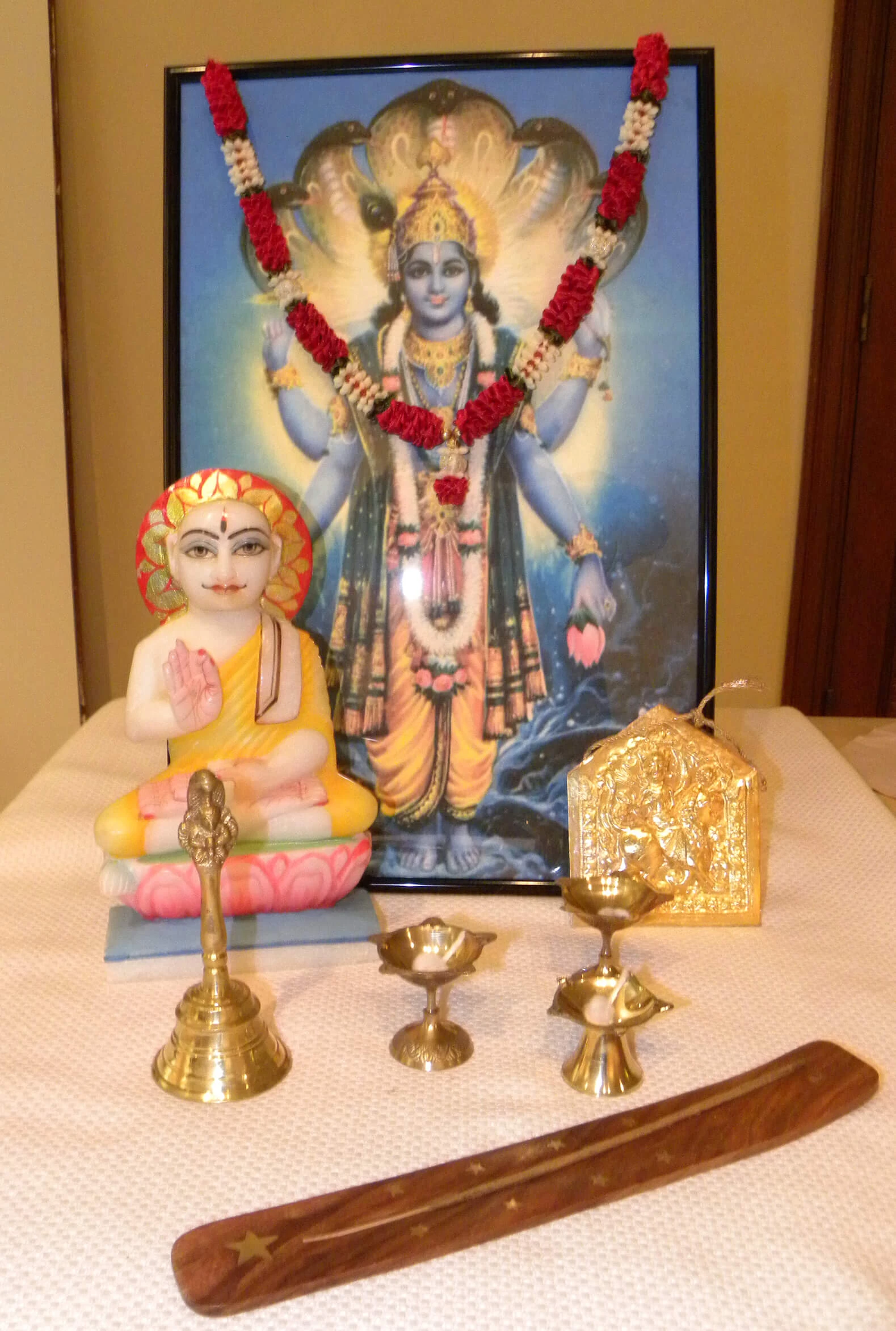 Home altar for prayers featuring brass objects, incense, and figurines of deities.