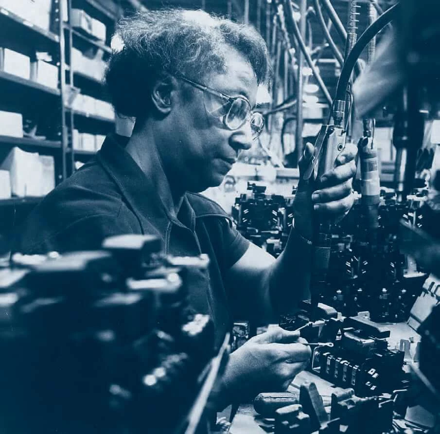 Picture of Ruth Waddell, an African American Woman, sitting at a desk surrounded by electronic components