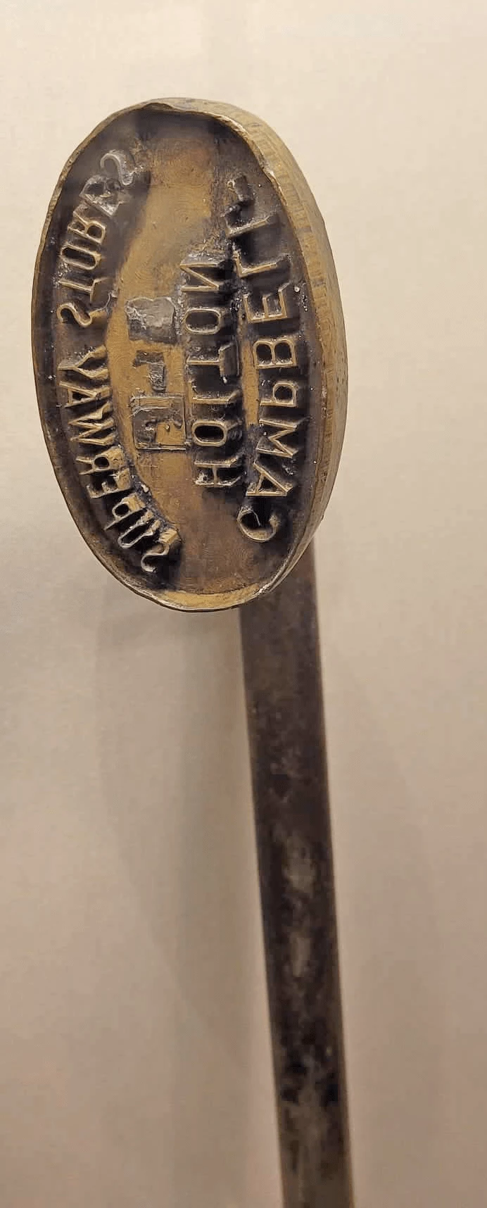 Metal stamp that has 'Campbell Holton Superway Stores' written backwards on it.